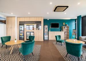 a lobby with green chairs and tables and a tv at All Suites Appart Hôtel Bordeaux Pessac in Pessac