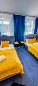 two beds in a hotel room with blue curtains at Great Polonia Wrocław Tumski in Wrocław