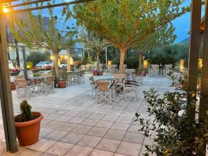an outdoor patio with tables and chairs and trees at Terpno Apartment in Leonidio