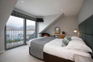 een slaapkamer met een groot bed en een balkon bij Kylesku Hotel in Kylestrome