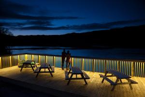 a person standing on a deck with three benches at Kylesku Hotel & Kylesku House, by Highland Coast Hotels in Kylestrome