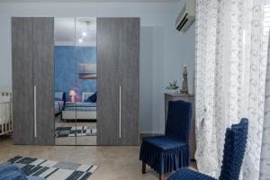 a bedroom with a glass door with two blue chairs at Appartamento Le Rondini in Siculiana