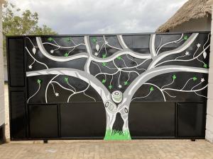 a gate with a painting of a tree on it at Mapeni Lodge in Kidenge