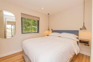 1 dormitorio con 1 cama blanca grande y espejo en Hygge at Vallum, en Newcastle