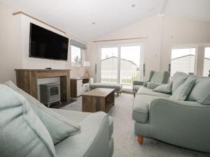 a living room with couches and a flat screen tv at Lodge at Chichester Lakeside 2 Bed in Chichester