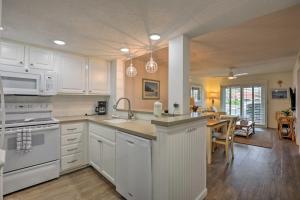 a kitchen with white cabinets and a table in it at Colorful Oceanside Condo with Beach Access! in Saint Augustine Beach