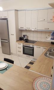 a kitchen with white cabinets and a stainless steel refrigerator at Byron House in Parga