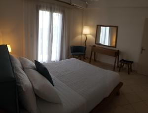a bedroom with a white bed with a mirror and a window at Byron House in Parga
