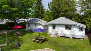 una casa con patio con mesa de picnic y sombrilla en Bel Air Cottages and Motel, en Sauble Beach