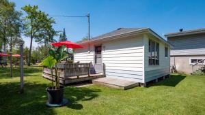a small house with a porch with a red umbrella at Bel Air Cottages and Motel in Sauble Beach