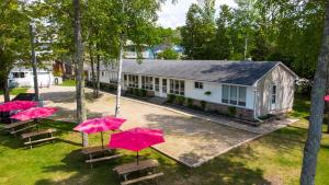 a group of tables with pink umbrellas in front of a building at Bel Air Cottages and Motel in Sauble Beach