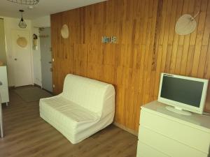 a living room with a white chair and a television at Chez Cyrielle et Christophe in Allevard