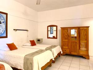 a hotel room with two beds and a mirror at Hotel Alegria in Cabarete
