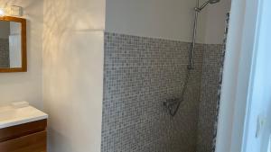 a bathroom with a shower with a tiled wall at Le M Hotel Marie Galante in Beauregard