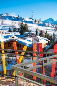 een hek met oranje en gele palen en met sneeuw bedekte daken bij PopAlp in L'Alpe-d'Huez