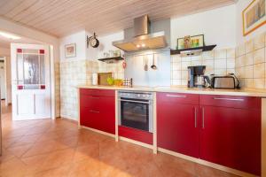 a large kitchen with red cabinets and a stove at Kajüte in Ihlow