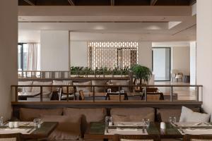 Helea Lifestyle Beach Resort في كاليثيا رودس: غرفة طعام مع طاولات وكراسي ومبنى