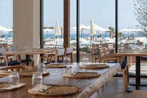 una sala da pranzo con tavoli, sedie e finestre di Helea Lifestyle Beach Resort a Calitea (Kallithea)