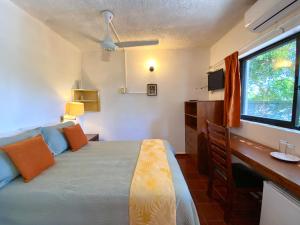 a bedroom with a bed and a desk and a window at Hotel Alegria in Cabarete