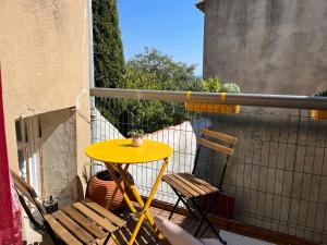 d'une table jaune et de deux chaises sur un balcon. dans l'établissement Atypique, à Châteauneuf-de-Gadagne