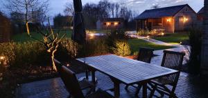 uma mesa de madeira e cadeiras num jardim à noite em WanT Logies: Ruime loft em Damme
