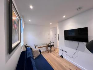 uma sala de estar com um sofá azul e uma televisão de ecrã plano em Chapel - Central Studio Apartment em Bath