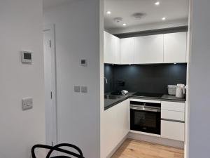 uma cozinha com armários brancos e um forno com placa de fogão em Chapel - Central Studio Apartment em Bath