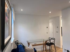 uma sala de estar com uma mesa de vidro e cadeiras em Chapel - Central Studio Apartment em Bath