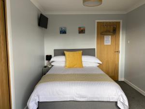 a bedroom with a bed with a yellow pillow on it at Innisfree Guest House in Fort William