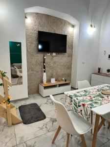 a living room with a table and a television on a wall at Chimera House in Catania