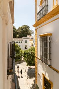 un callejón con dos personas caminando por una calle en Santacruz Hostal Plaza, en Sevilla