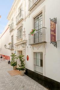 a white building with balconies and potted plants on a street at Santacruz Hostal Plaza in Seville