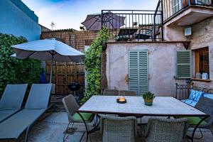 a patio with a table and an umbrella at Albuqassim a modern townhouse in Pollensa, with heated pool in Pollença
