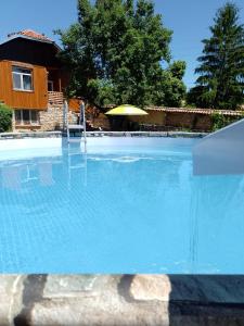 una gran piscina azul con sombrilla en Вила Нина в Крамолин en Kramolin