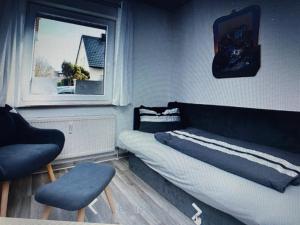 a bedroom with a bed and a chair and a window at Ferienwohnung Klenk in Ostfildern