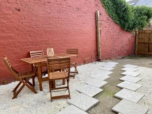 une table et des chaises en bois à côté d'un mur en briques rouges dans l'établissement 50 Biddlestone Road Heaton, à Newcastle upon Tyne