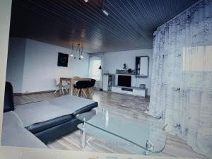 uma sala de estar com um sofá e uma mesa de vidro em Ferienwohnung Klenk em Ostfildern