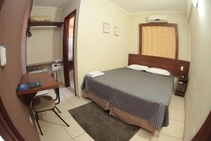 a small bedroom with a bed and a desk at Druds Hotel in Três Lagoas