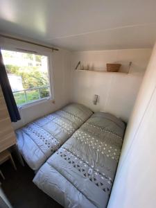 Cama en habitación pequeña con ventana en MOBIL HOME Climatisé G058 en Aureilhan