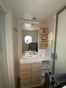 La salle de bains est pourvue d'un lavabo et d'un miroir. dans l'établissement MOBIL HOME Climatisé G058, à Aureilhan