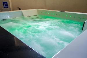 a bath tub filled with blue water with people in it at Farys - świetna lokalizacja, sauna, jacuzzi, piękne widoki z okien in Krynica Zdrój