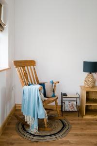 a wooden rocking chair with a blue blanket on it at Modern self catering apartment, Miltown Malbay in Milltown Malbay