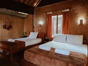 a hotel room with two beds and a window at Jembrana Bali Homestay in Pengambengan