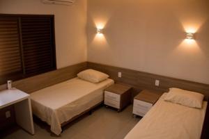 um quarto com duas camas e duas luzes na parede em Rosa Vilma Hotel em Chapadão do Sul
