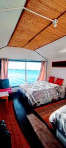 a bedroom with two beds and a large window at Titicaca wasy lodge in Puno