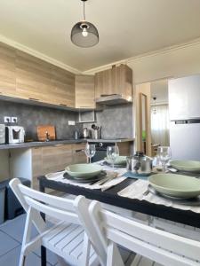 eine Küche mit einem Tisch mit Tellern und Weingläsern in der Unterkunft Appartement lumineux et traversant in Montauban