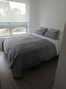 een bed met een zwart-wit gestreept dekbed in een slaapkamer bij Apto en Punta del Este con Piscina Climatizada!! in Punta del Este