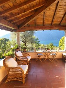 d'une terrasse avec des chaises et une table offrant une vue sur l'océan. dans l'établissement Casa Intignano - Camera con bagno e portico vista lago, à Tremezzo