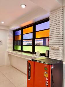 een keuken met 2 ramen en een oranje koelkast bij Baankasemsuk Resort 般咔 深宿 in Patong Beach