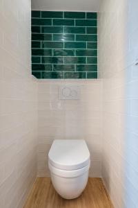 a bathroom with a toilet and a green tile wall at COSY STUDIO RENOVÉ 150m de MONACO in Beausoleil